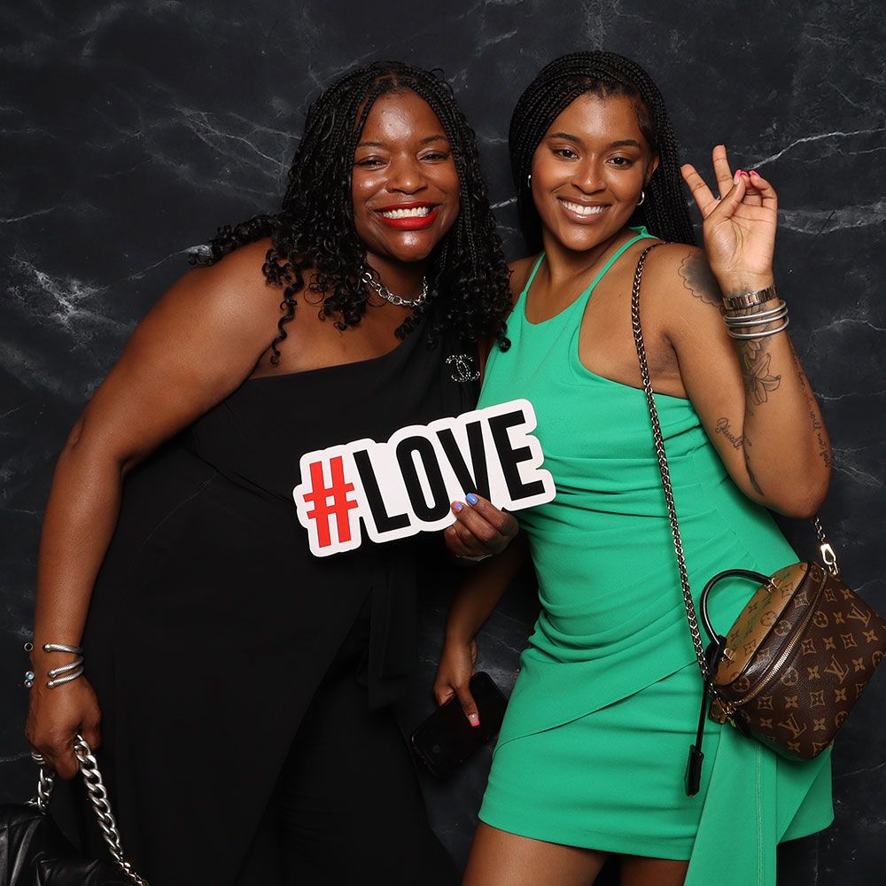 Guests posing at a wedding photo booth with a #LOVE sign