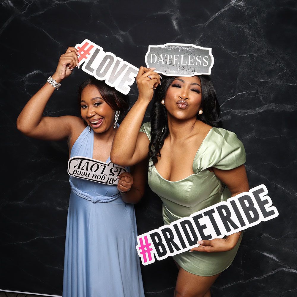 Guests posing at a wedding photo booth with a Bride Tribe sign
